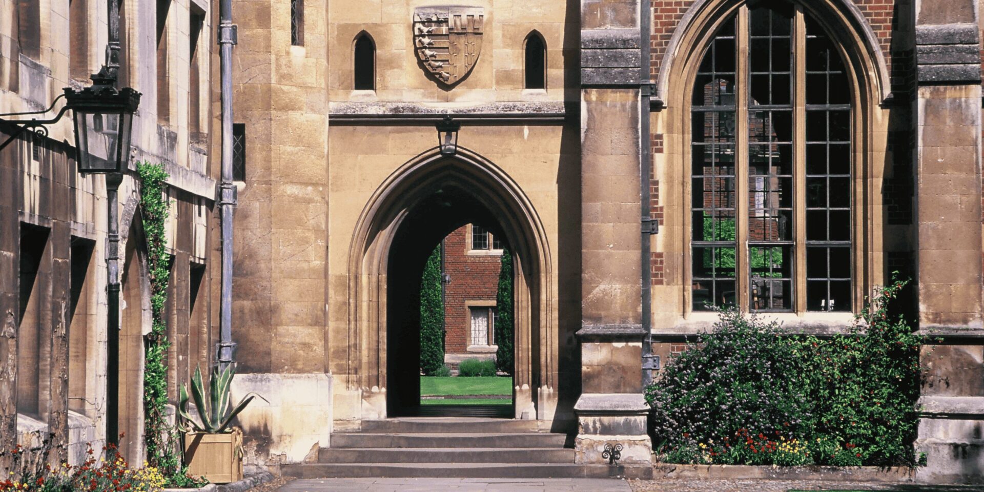 A group of students sitting on the grass, engaged in study and discussion, with Cambridge University buildings in the background.