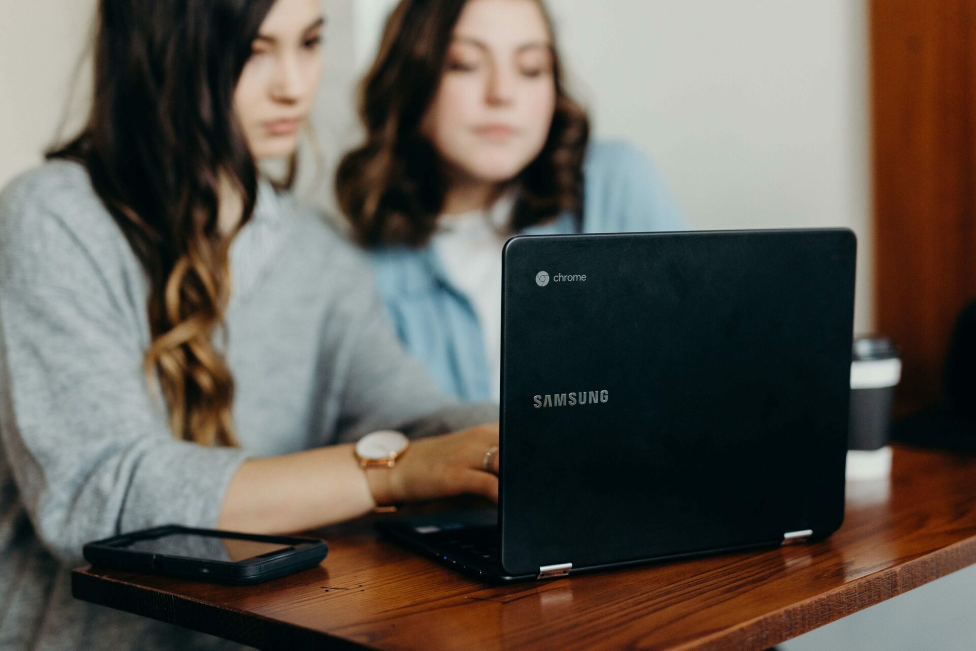 two woman sharing a laptop