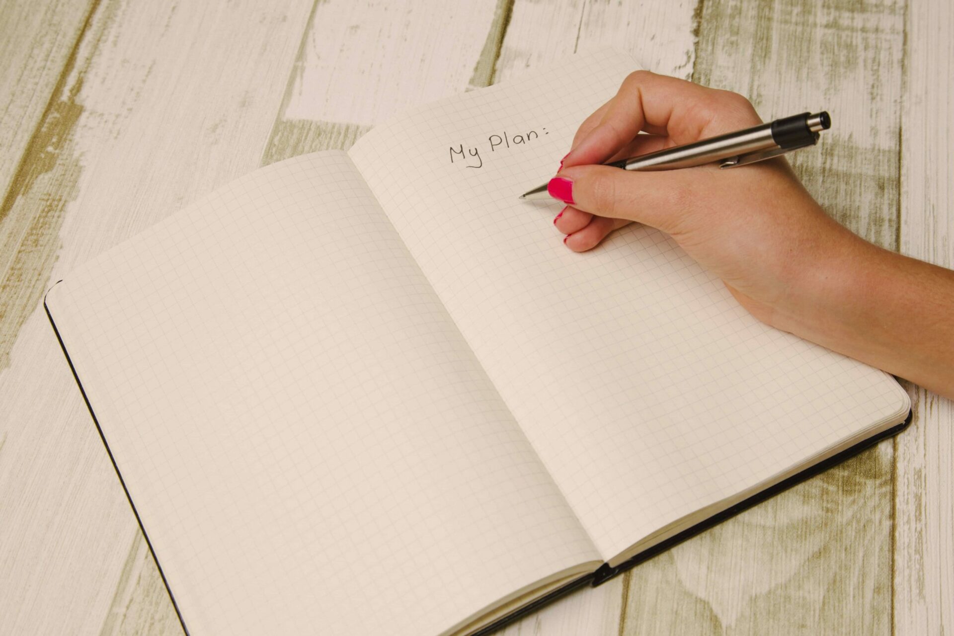 A person writing in a grid-lined notebook