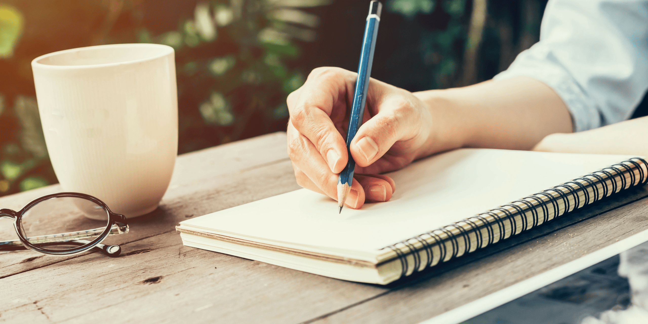 Writing in a notebook with a cup of coffee