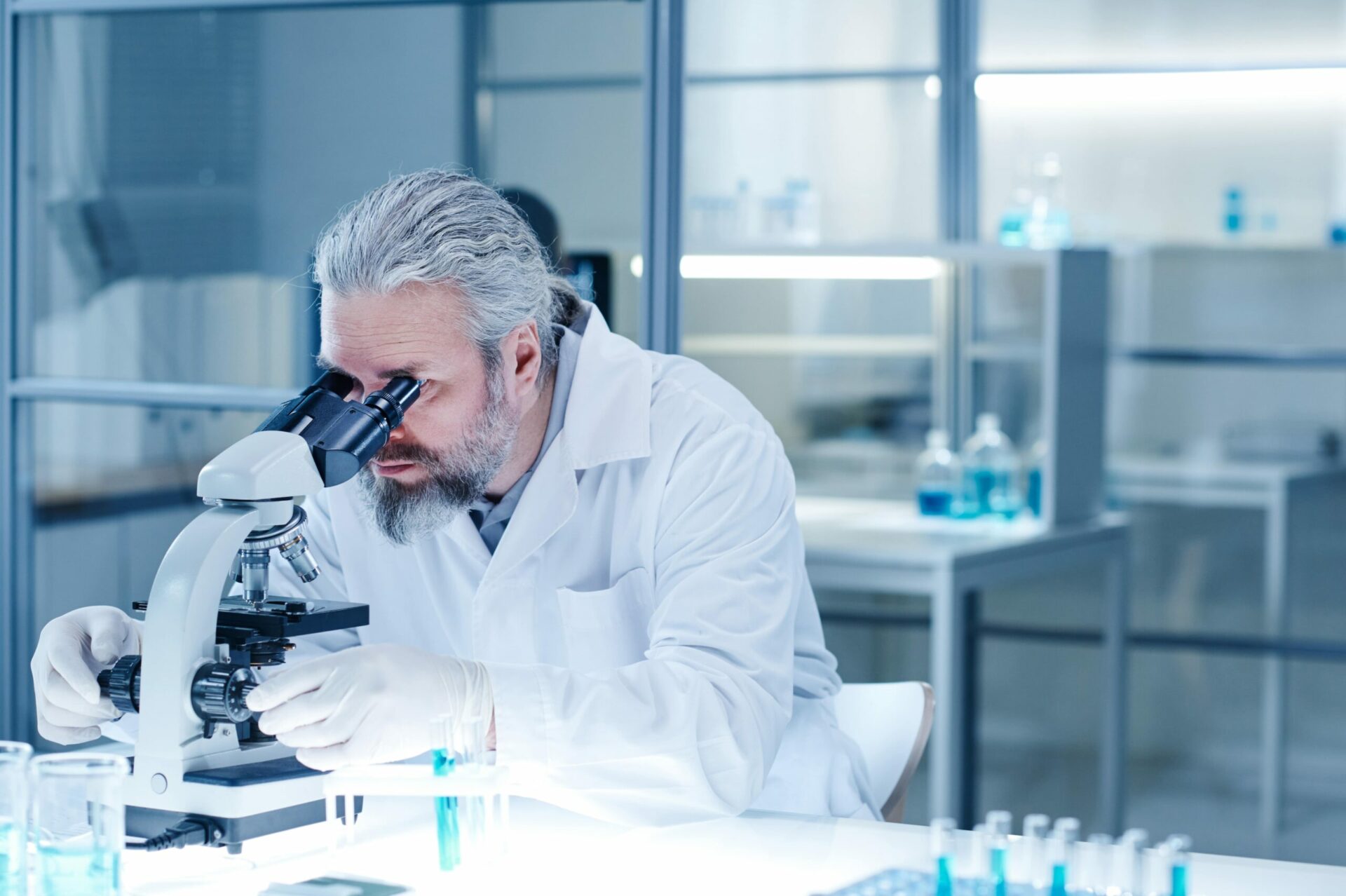 Male pathologist under microscope in lab