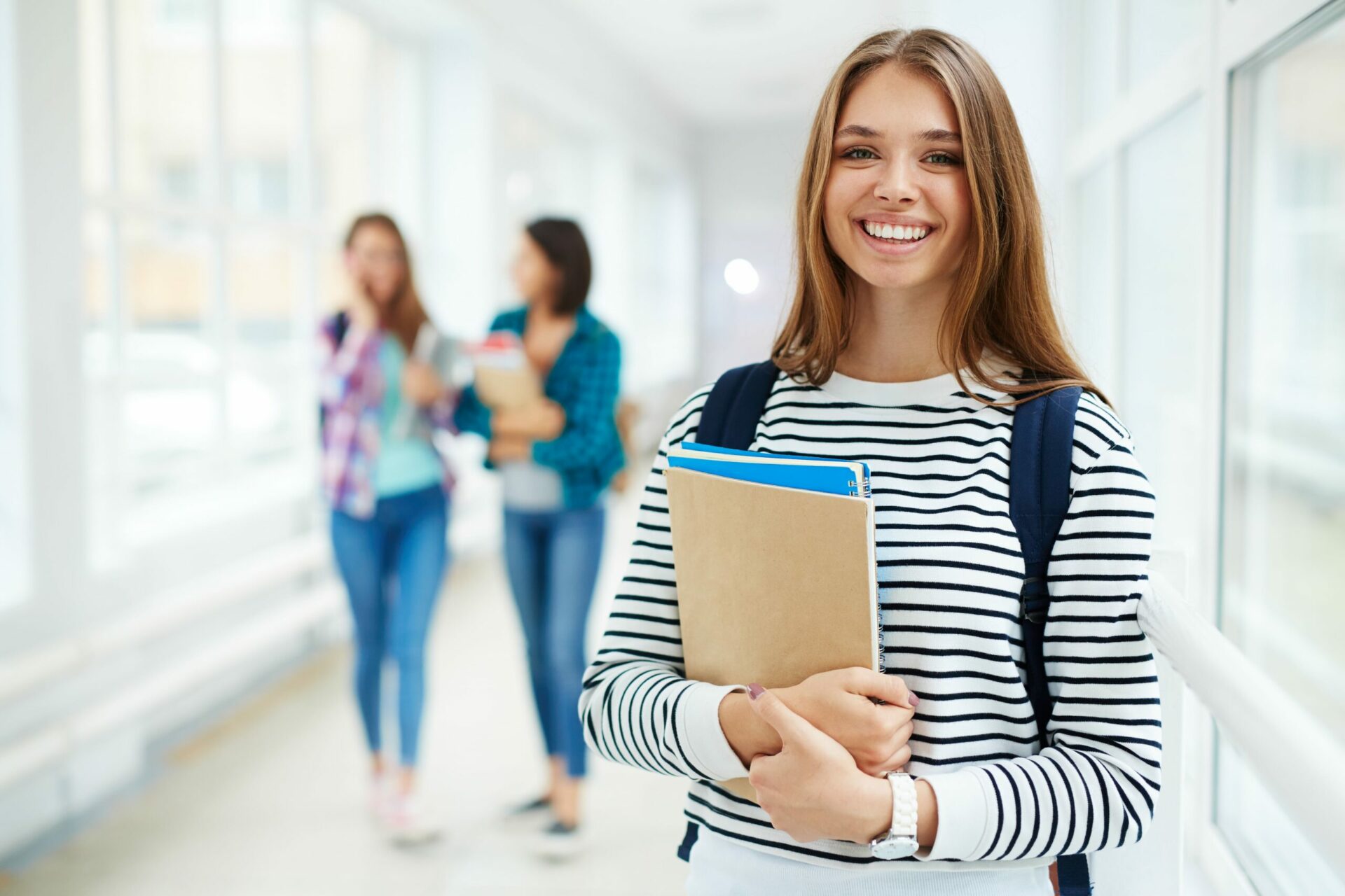 female carrying notebooks on hallway