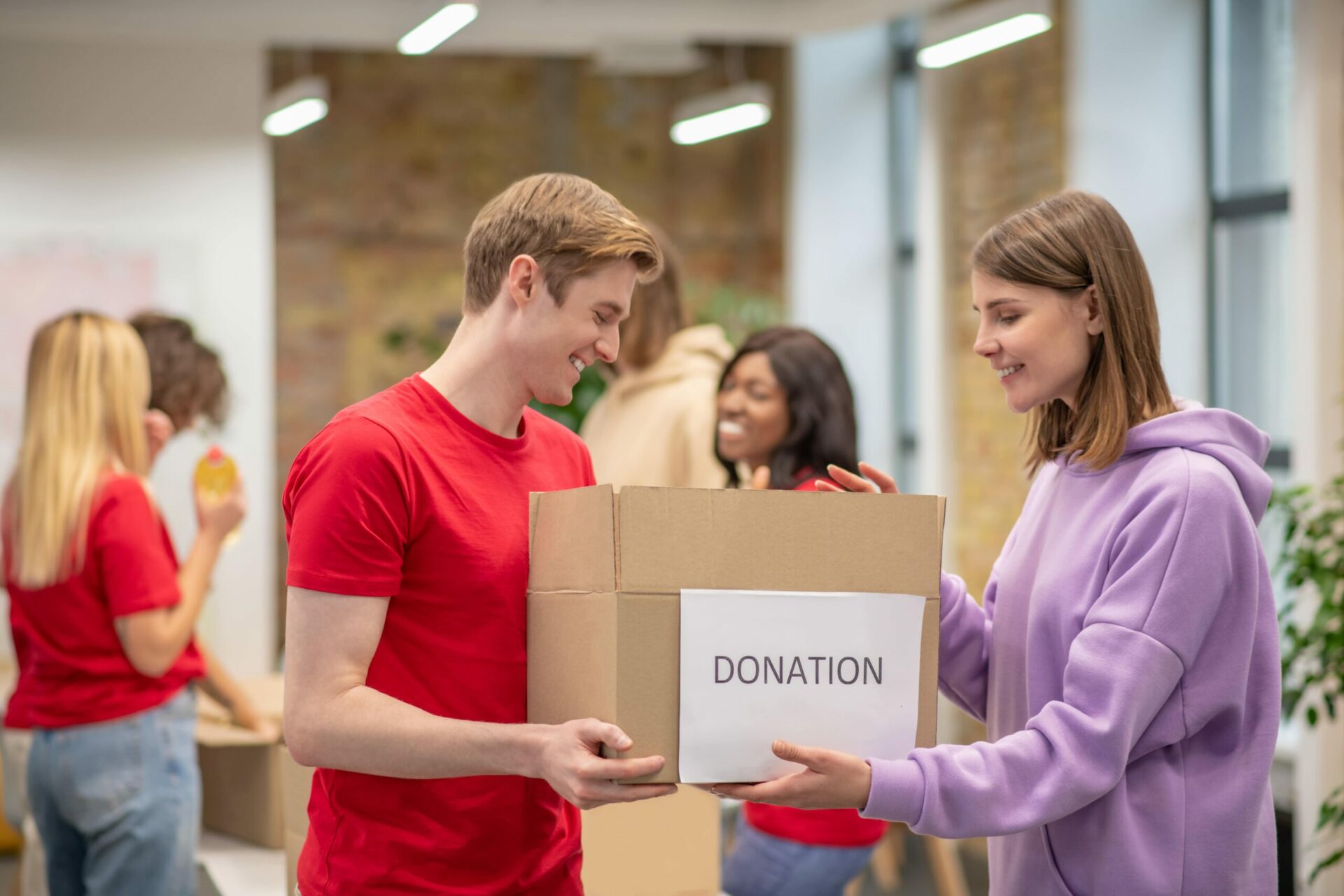 Man and woman passing donation box