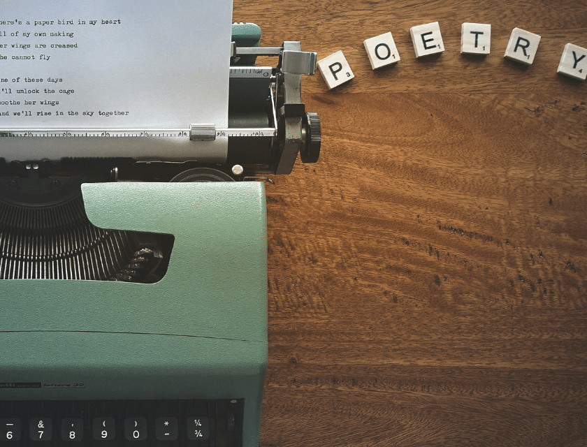 A typewriter and letter tiles that says 'Poetry'.