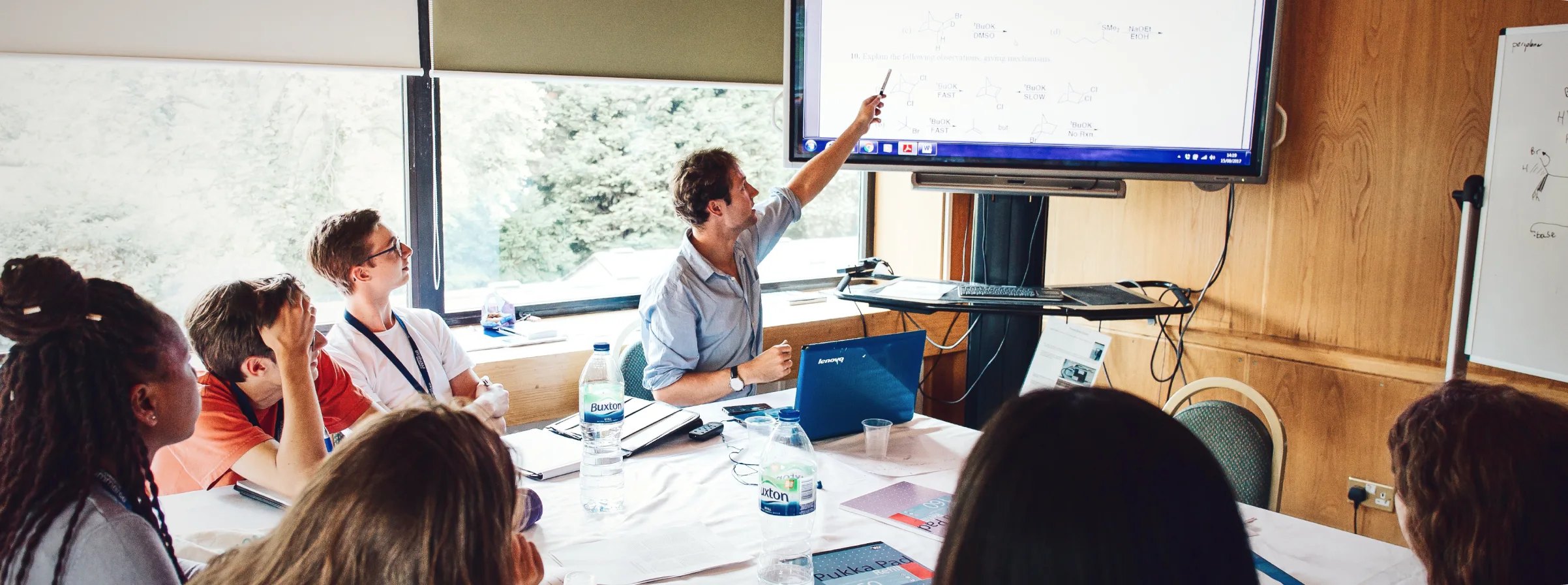 A man teaching to the students while pointing on his presentation