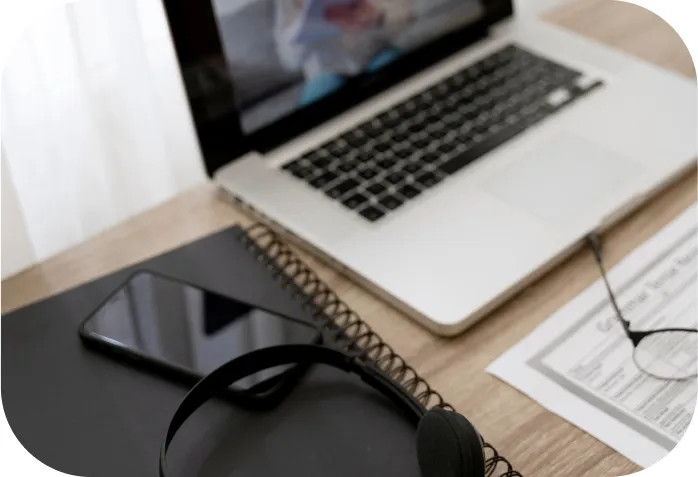 A laptop, notebook, headphone, and a phone on a table