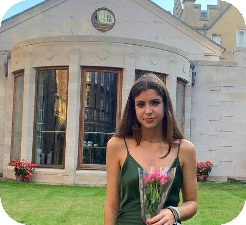 Adriadna M holding flowers in front of a house