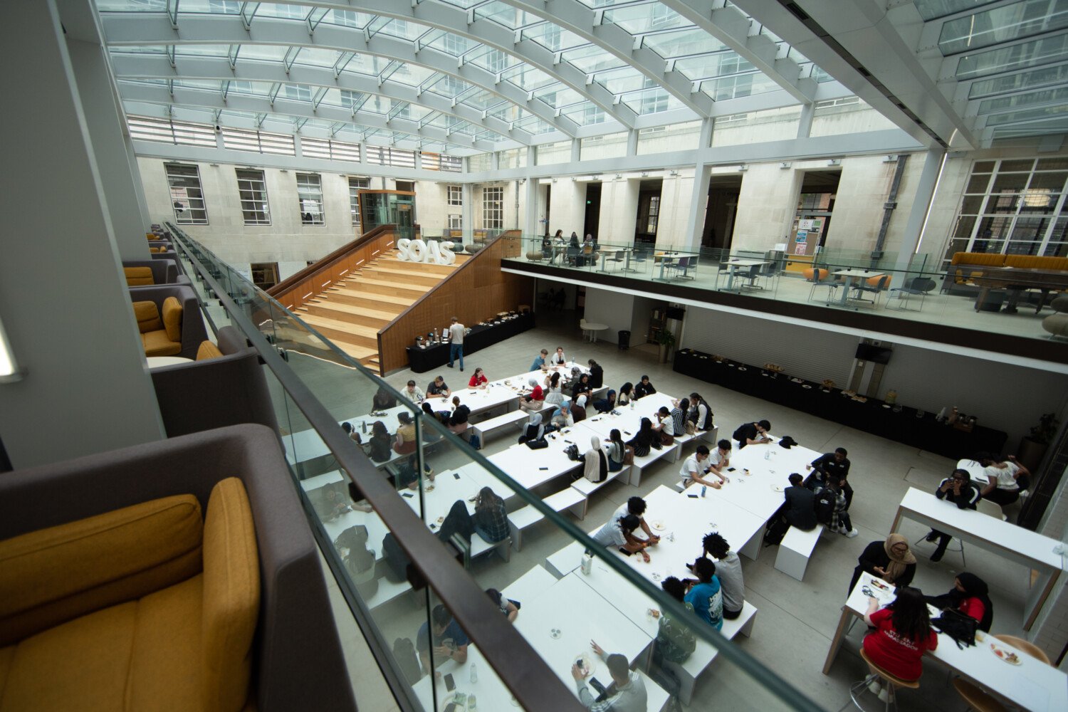 a group of people sitting at tables in a room with glass walls