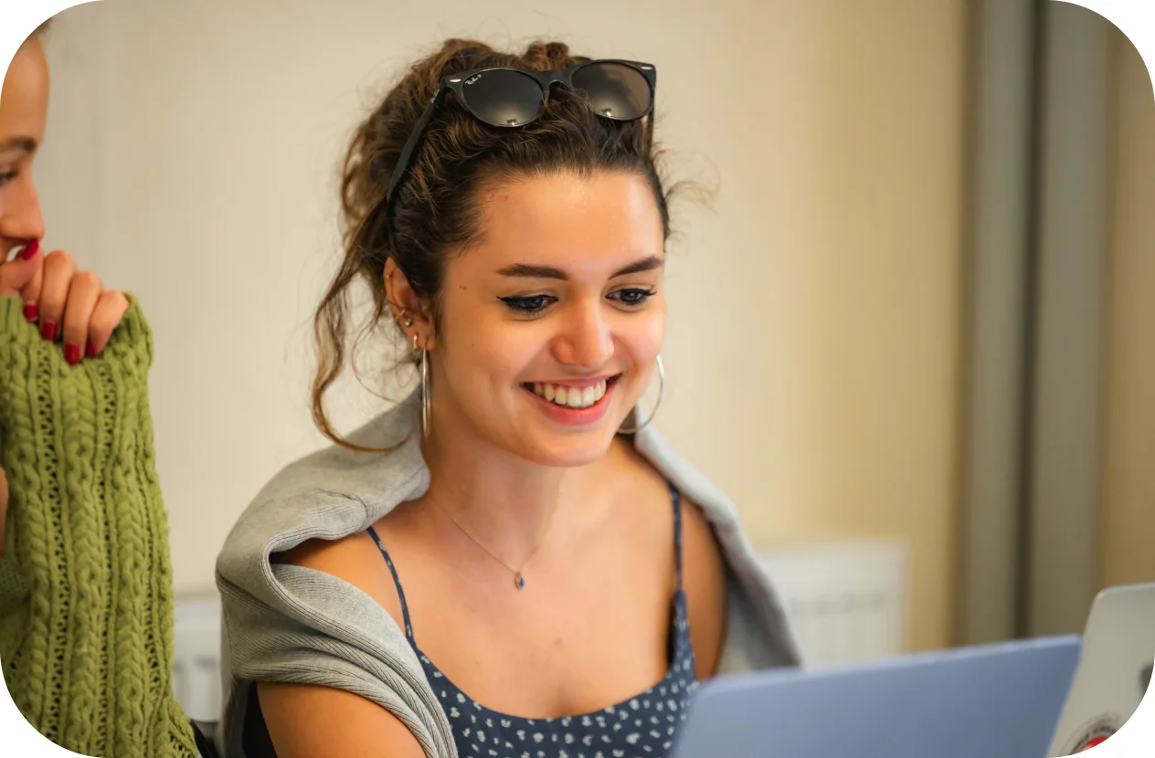 A woman smiling while looking at her laptop.