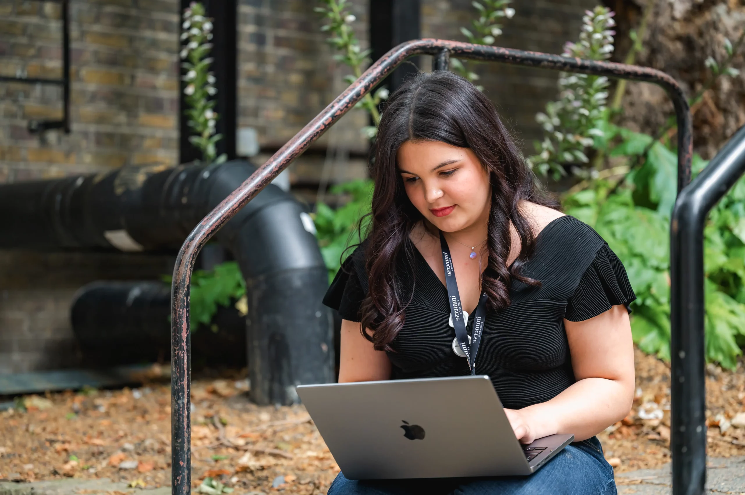 Immerse Education student participant sitting on stairs with laptop