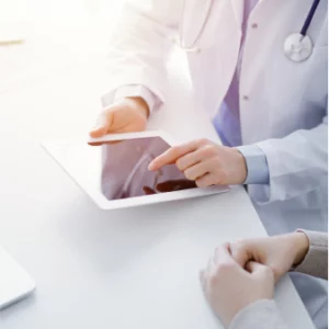 A person wearing a lab coat and stethoscope while holding a tablet