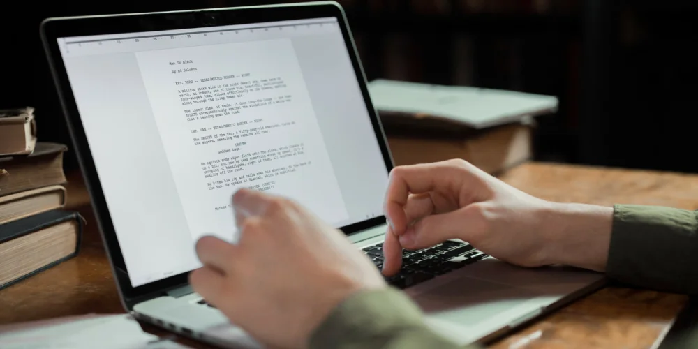 A person typing on his laptop with an opened document.