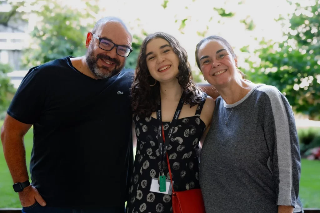 An Immerse Education student poses with her parents in the gardens of Queens College Cambridge