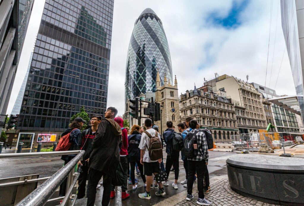 A group of Year 12 students exploring London's financial district as part of banking work experience. Students stand with their back to us facing the Gherkin.