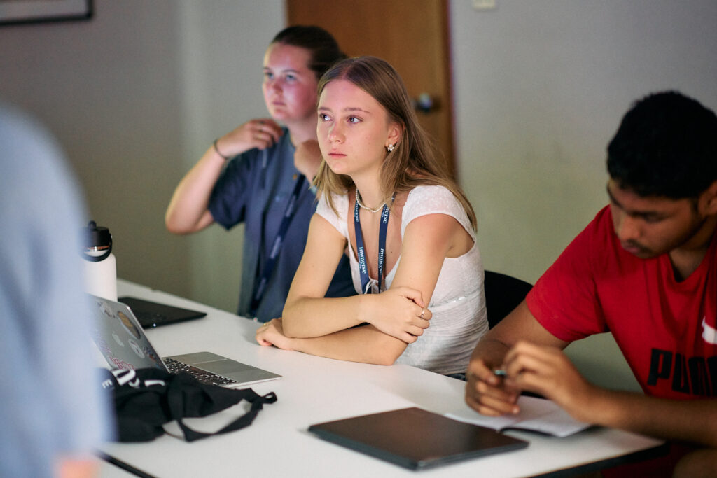 A year 12 student listens attentively in the classroom, surrounded by fellow classmates and laptops as part of an Immerse career experience programme.
