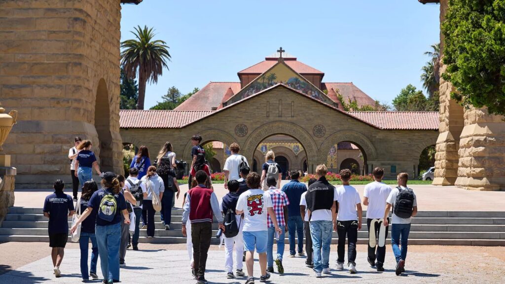 A group of students walking towards the steps of a church-like structure as part of a tour.
