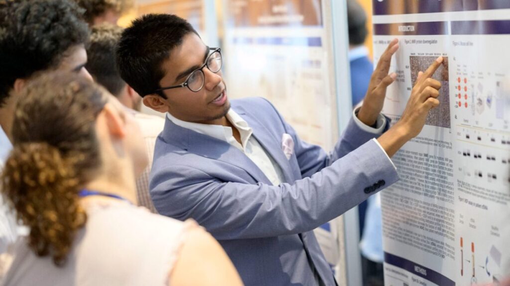 A person explaining a poster to a group of onlookers