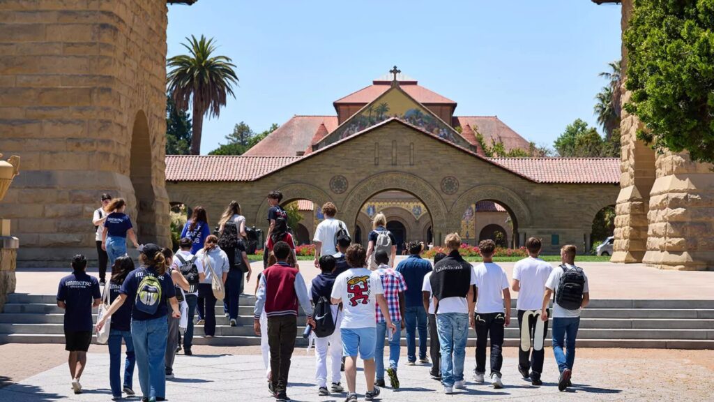 A group of students walking towards the steps of a church-like structure as part of a tour.