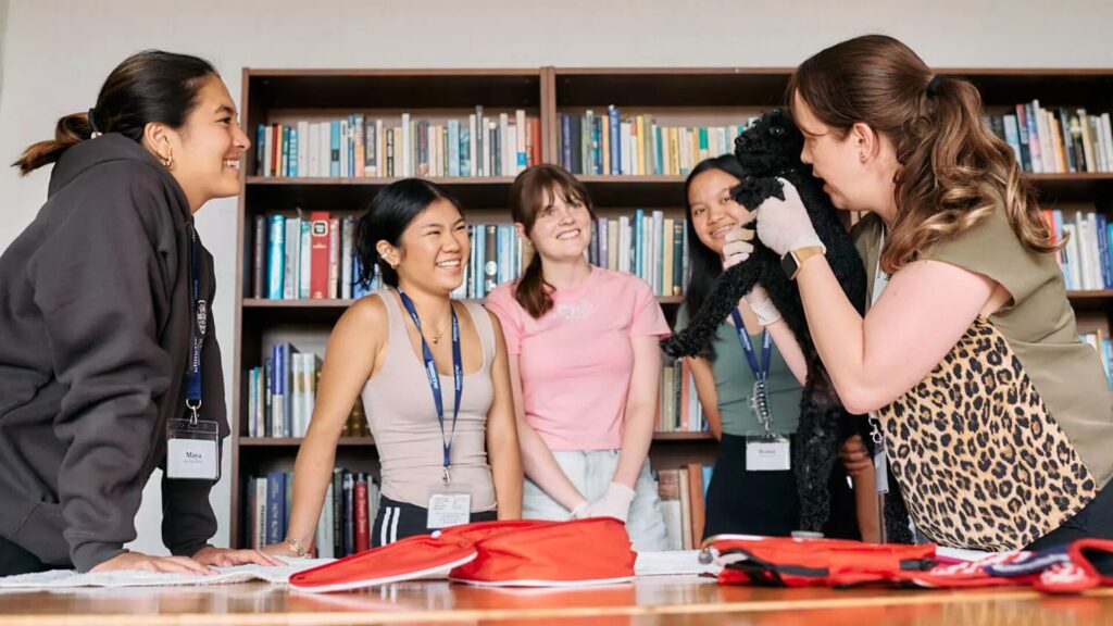 A group of students listening to an instructor holding a dog