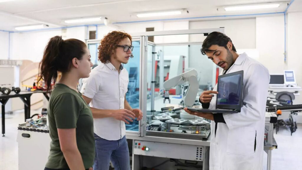 An instructor displaying something on a laptop to two students