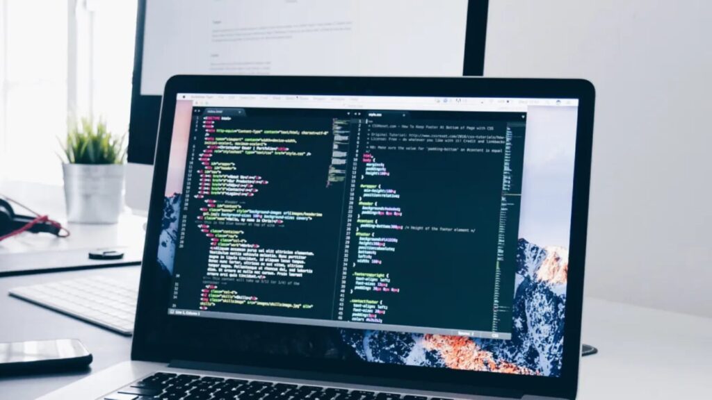 A laptop on a desk with lines of code on the display