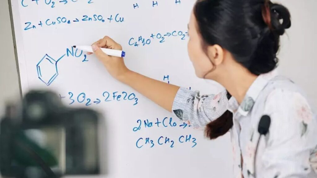 A faculty member teaching chemistry on a whiteboard at Immerse's summer school.