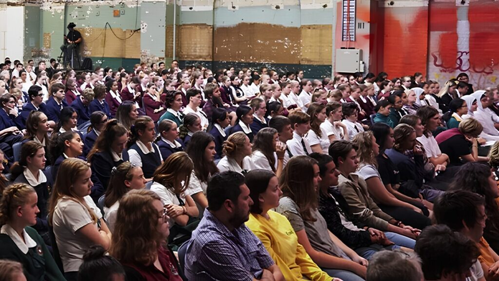 A group of students sitting in a lecture hall and listening attentively